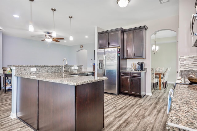 kitchen with light hardwood / wood-style flooring, stainless steel fridge, sink, dark brown cabinets, and light stone counters