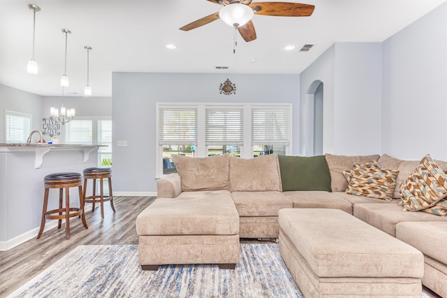 living room with ceiling fan with notable chandelier and light wood-type flooring