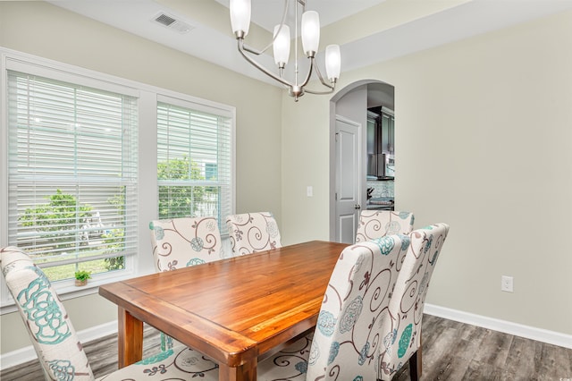 dining space with dark wood-type flooring, a chandelier, and a healthy amount of sunlight