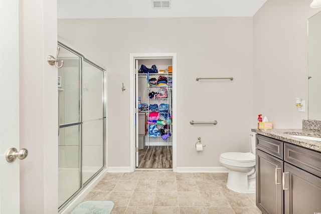 bathroom featuring toilet, vanity, and an enclosed shower