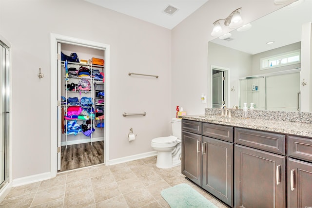 bathroom featuring tile patterned floors, toilet, vanity, and walk in shower