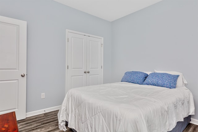 bedroom with dark hardwood / wood-style flooring and a closet