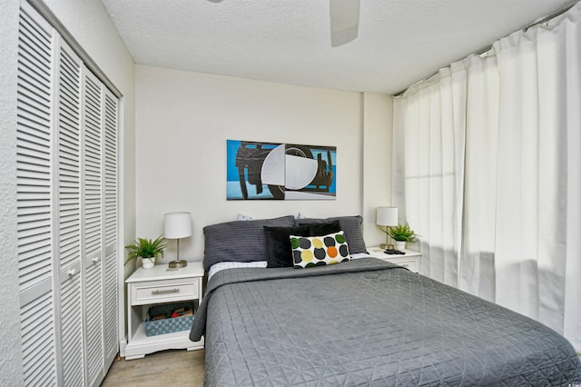 bedroom with a textured ceiling, ceiling fan, and hardwood / wood-style flooring