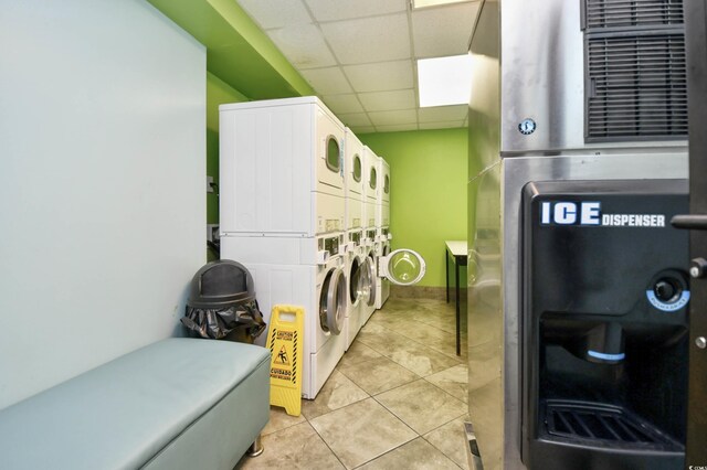 clothes washing area with light tile patterned floors and stacked washing maching and dryer