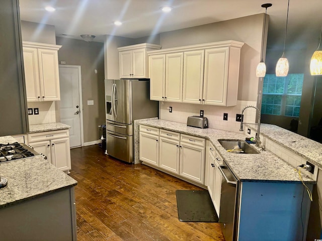 kitchen featuring light stone countertops, sink, stainless steel appliances, decorative light fixtures, and dark hardwood / wood-style floors