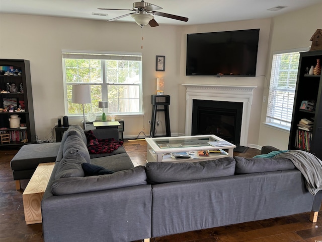 living room featuring dark wood-type flooring, ceiling fan, and a healthy amount of sunlight