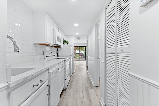 kitchen featuring backsplash, light hardwood / wood-style flooring, light stone counters, white appliances, and white cabinets