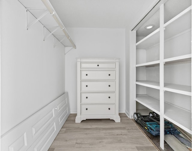 walk in closet with light hardwood / wood-style floors