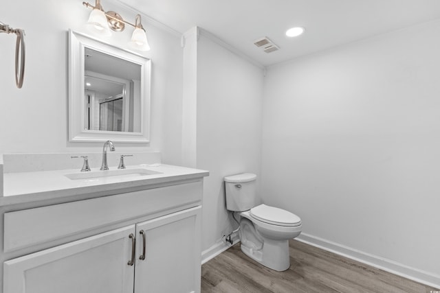 bathroom with toilet, vanity, ornamental molding, walk in shower, and hardwood / wood-style flooring