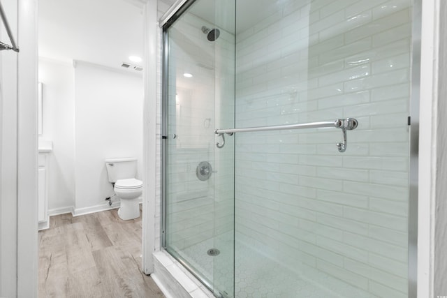 bathroom featuring hardwood / wood-style flooring, toilet, and a shower with shower door