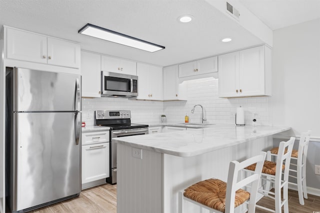 kitchen with stainless steel appliances, sink, white cabinets, and kitchen peninsula