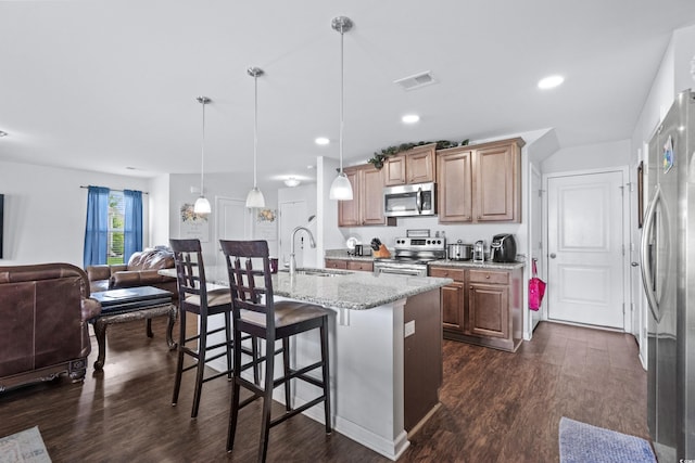 kitchen featuring a sink, a kitchen bar, dark wood-style floors, stainless steel appliances, and visible vents