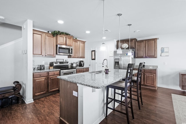 kitchen featuring dark wood-style floors, a sink, stainless steel appliances, and a breakfast bar area