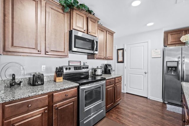 kitchen featuring dark wood-style flooring, stainless steel appliances, light stone counters, and recessed lighting