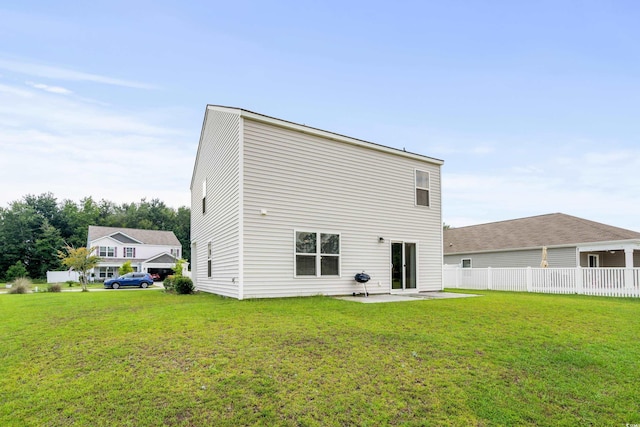 back of property featuring fence, a lawn, and a patio area
