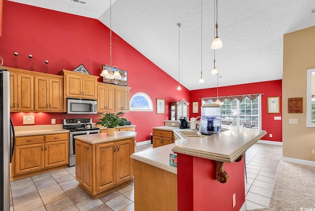 kitchen featuring sink, stainless steel appliances, a center island with sink, and hanging light fixtures