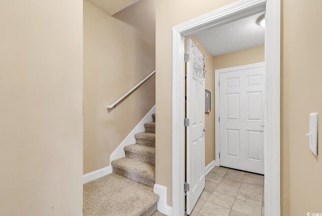 stairs with tile patterned flooring and a textured ceiling