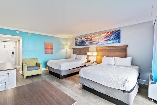 bedroom with light wood-type flooring, crown molding, and radiator heating unit