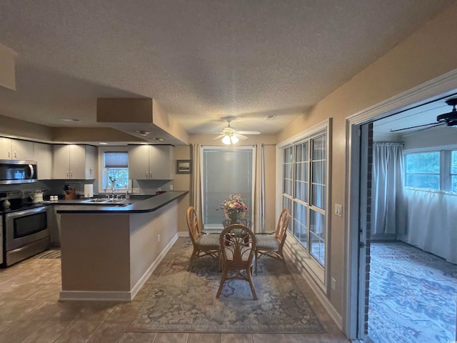 kitchen with range with electric stovetop, sink, tile patterned flooring, kitchen peninsula, and ceiling fan