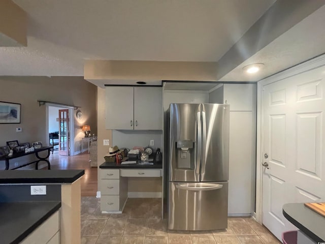 kitchen with light tile patterned flooring, white cabinetry, and stainless steel fridge