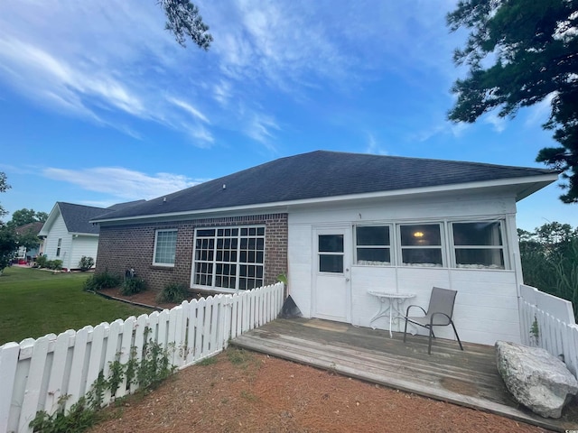 back of property with a wooden deck and a lawn