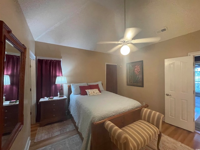 bedroom featuring hardwood / wood-style flooring, a textured ceiling, lofted ceiling, and ceiling fan