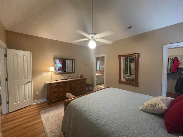 bedroom with a closet, hardwood / wood-style flooring, ceiling fan, ensuite bathroom, and a textured ceiling