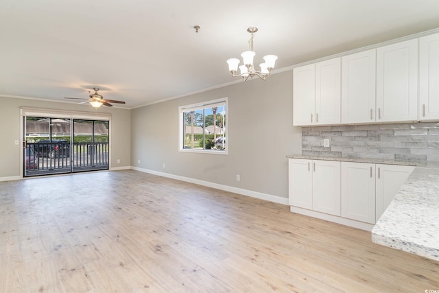 unfurnished living room with ceiling fan with notable chandelier, light hardwood / wood-style flooring, and ornamental molding