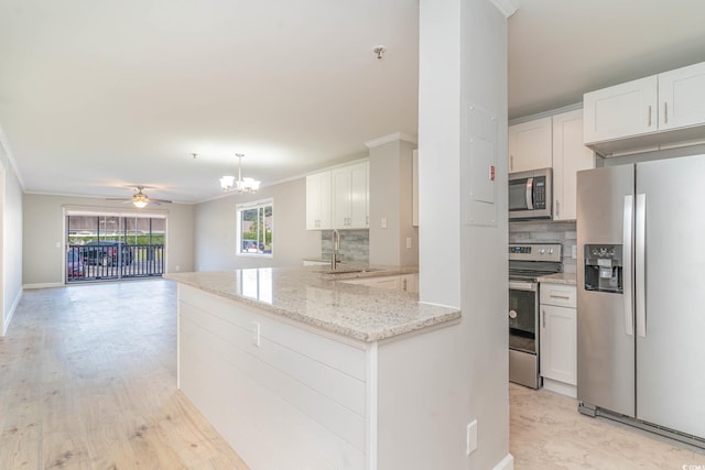 kitchen with light hardwood / wood-style flooring, ceiling fan with notable chandelier, tasteful backsplash, and stainless steel appliances