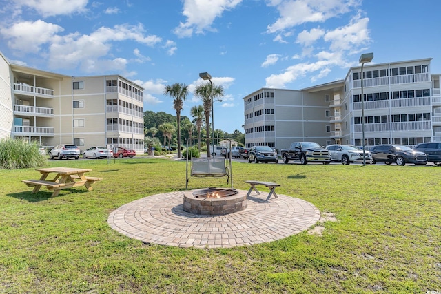 view of community with a yard and an outdoor fire pit