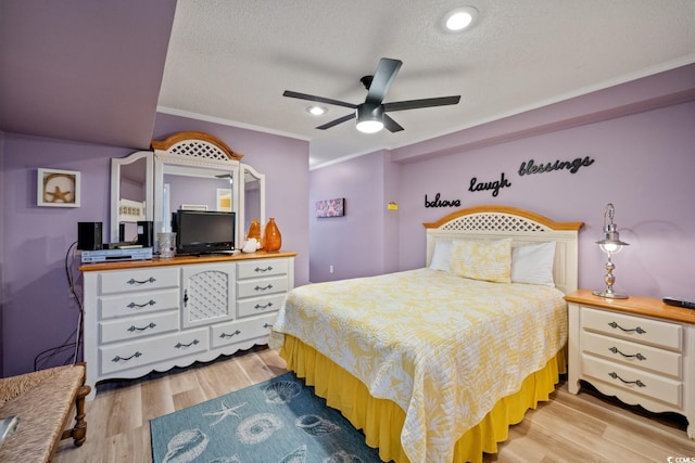 bedroom with a textured ceiling, light hardwood / wood-style flooring, ceiling fan, and ornamental molding