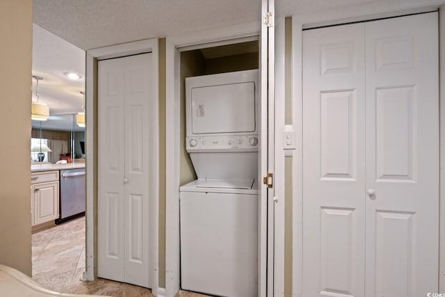 washroom with a textured ceiling and stacked washer / dryer