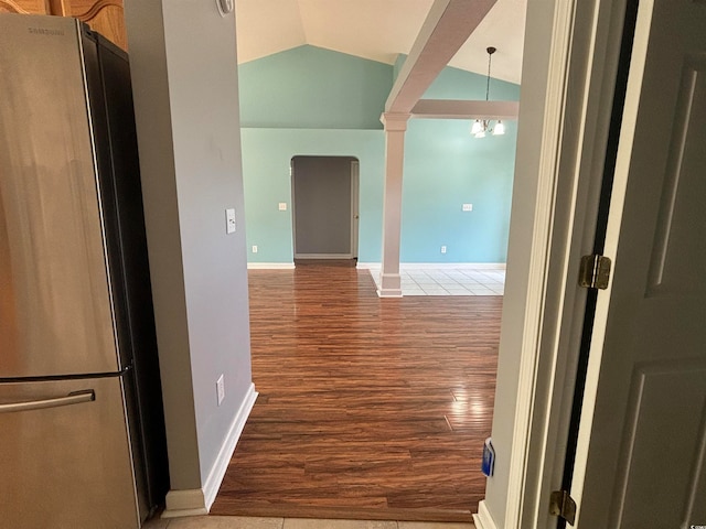 hallway with a notable chandelier, vaulted ceiling, dark hardwood / wood-style flooring, and ornate columns