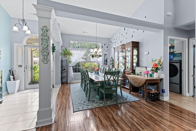 dining space with a notable chandelier, hardwood / wood-style floors, high vaulted ceiling, and washer / dryer