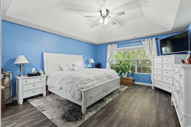 bedroom with ceiling fan, a textured ceiling, a raised ceiling, and dark hardwood / wood-style floors