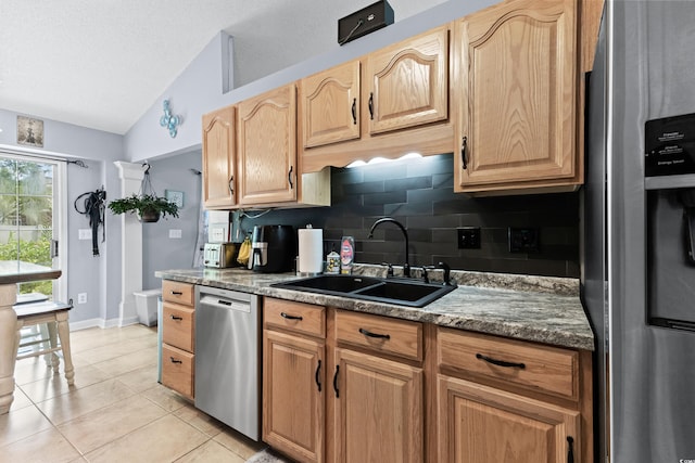 kitchen featuring tasteful backsplash, light tile patterned flooring, sink, vaulted ceiling, and appliances with stainless steel finishes