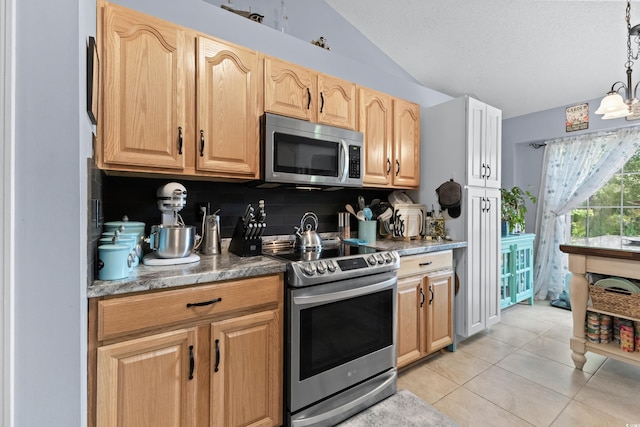 kitchen featuring pendant lighting, a textured ceiling, light tile patterned flooring, vaulted ceiling, and appliances with stainless steel finishes