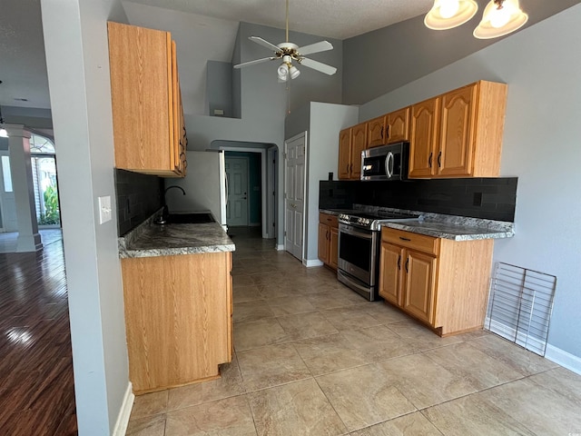 kitchen with ceiling fan, tasteful backsplash, high vaulted ceiling, appliances with stainless steel finishes, and light wood-type flooring