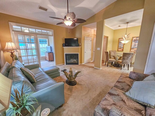 living room featuring ceiling fan with notable chandelier, a textured ceiling, and light colored carpet