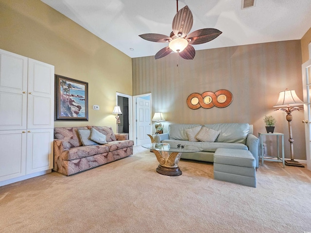 living room with ceiling fan, light colored carpet, and a towering ceiling