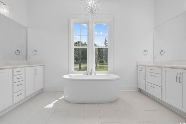 full bath with vanity, a chandelier, a freestanding bath, and baseboards