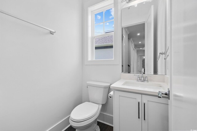 bathroom with toilet, vanity, and baseboards