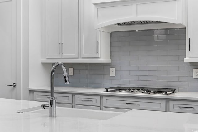 kitchen featuring tasteful backsplash, stainless steel gas stovetop, white cabinetry, and custom exhaust hood