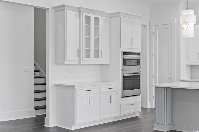kitchen with stainless steel double oven, light countertops, white cabinets, and dark wood-style flooring