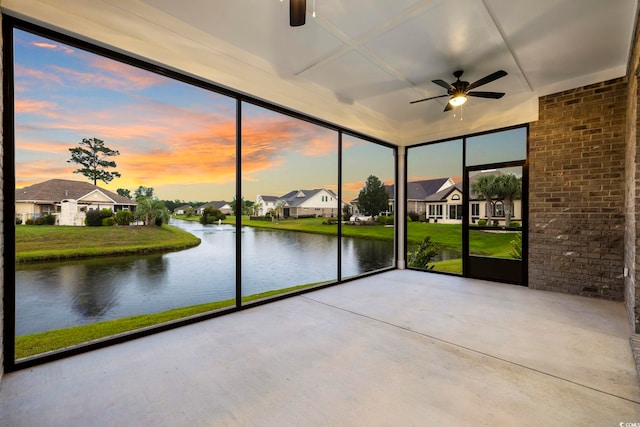 unfurnished sunroom featuring a water view, plenty of natural light, and ceiling fan