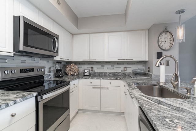 kitchen with appliances with stainless steel finishes, stone counters, sink, and white cabinets