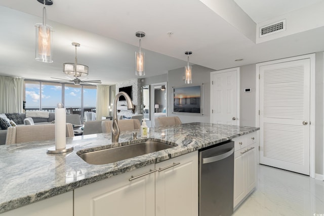 kitchen featuring light stone counters, ceiling fan, hanging light fixtures, dishwasher, and sink