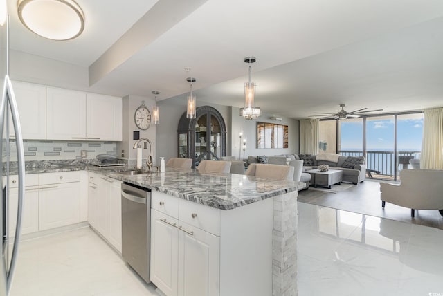 kitchen with stainless steel appliances, stone countertops, ceiling fan, sink, and white cabinetry