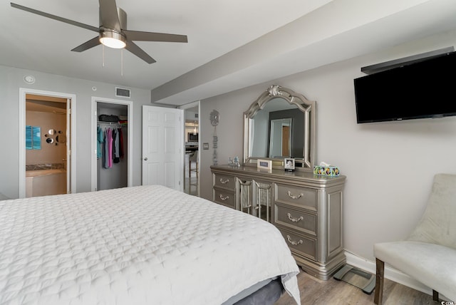 bedroom with light hardwood / wood-style flooring, ceiling fan, a walk in closet, ensuite bath, and a closet