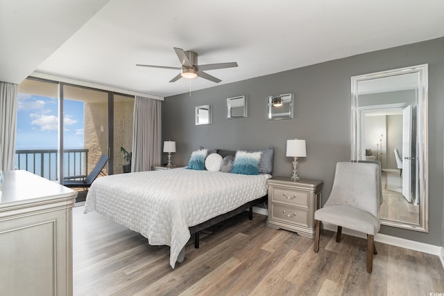 bedroom featuring ceiling fan, a wall of windows, access to exterior, and wood-type flooring